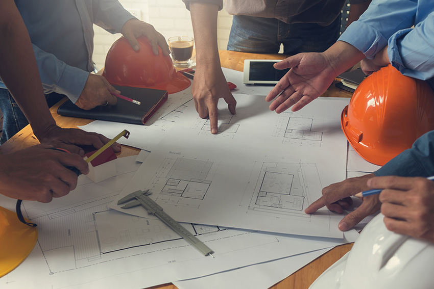 A team of commercial engineers and architects looking over and discussion construction schematics