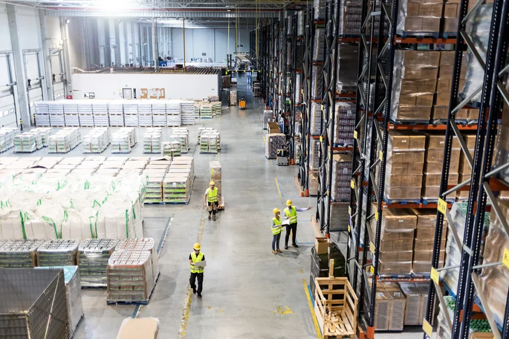 A birds-eye view of the interior of a warehouse filled with storage racks and workers, designed for efficiency