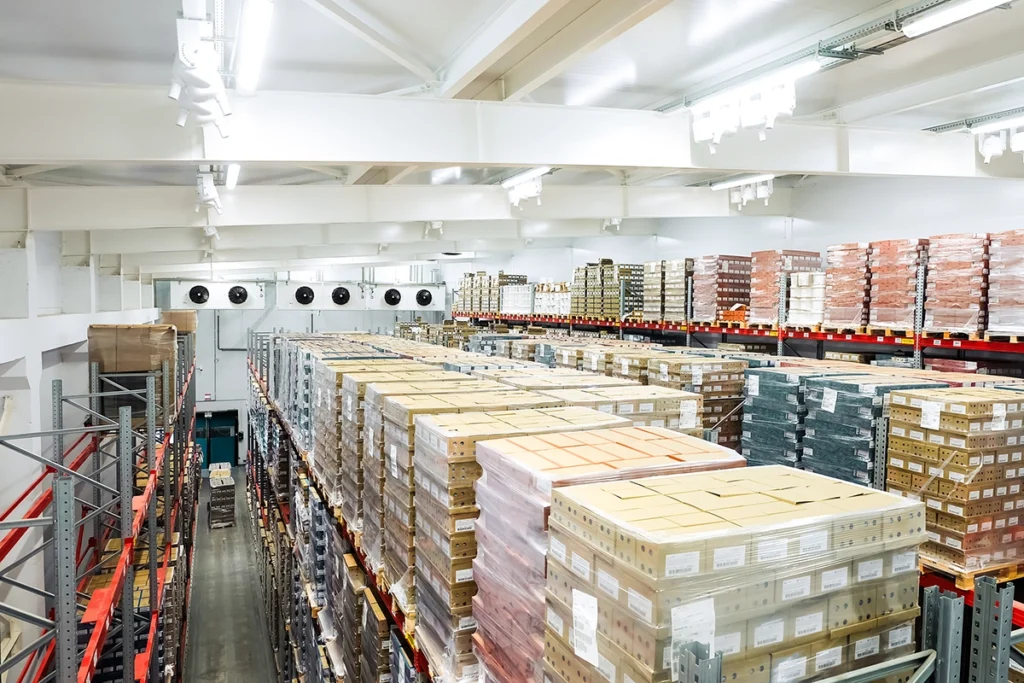 The interior of a large refrigerated cold storage warehouse, filled with racks and boxes