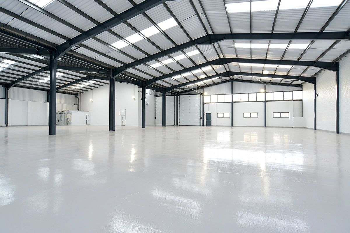 The interior of a newly constructed warehouse, with white floors and bright LED lights